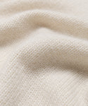 Close-up of the Cashmere Kate V-Neck features soft, cream-colored cashmere knit fabric with a visible textured pattern and gentle folds, highlighting its cozy and warm feel.