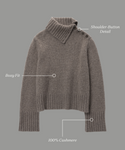 The Cashmere Jackie Sweater is a gray, boxy-fit piece crafted from 100% cashmere, featuring a luxe knit texture, ribbed cuffs and hem, and stylish shoulder-button detail. Labels highlight Boxy Fit and Shoulder-Button Detail.
