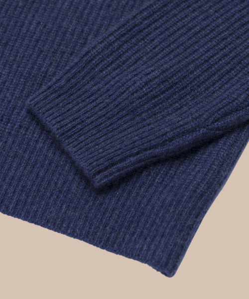 Close-up of the ribbed cuff and hem of the Cropped Cashmere Cocoon Cardigan in navy blue, shown on a beige background.