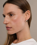 A woman with straight light brown hair and a white top wears Felix Dome Hoops in a close-up profile against a beige background.