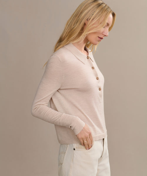 A woman with long blonde hair stands in profile against a neutral background, wearing the Grayson Pullover in light beige and cream-colored pants.