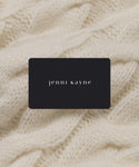 An E Gift Card with “jenni kayne” in white lowercase letters sits atop a cream cable-knit fabric—a timeless present for any occasion.