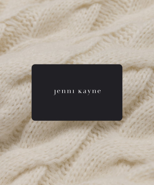 An E Gift Card with “jenni kayne” in white lowercase letters sits atop a cream cable-knit fabric—a timeless present for any occasion.