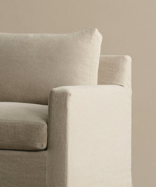 A close-up of the armrest, seat, and back cushion of the Harbor Chair in Drift Linen—modern beige upholstery inspired by Jenni Kayne Furniture—set against a plain beige background.