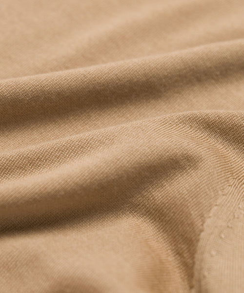 A close-up of the Mercer Crewneck highlights its luxe fabric, light brown color, textured weave, and soft folds—a timeless classic in every detail.