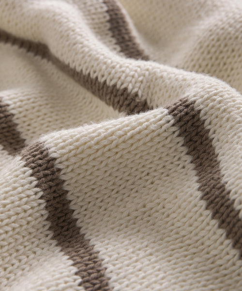 A close-up of the Chloe Crewneck, a soft cream-colored Peruvian cotton sweater featuring horizontal brown stripes and a subtly wavy texture.