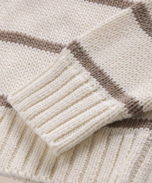 Close-up of the Chloe Crewneck, a cream-colored sweater with brown horizontal stripes. The ribbed cuff and hem highlight the detailed stitching and texture of Peruvian cotton yarn.