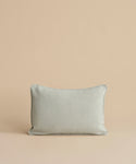 The Adler Lumbar Pillow, featuring a light gray linen blend with dark piping, is displayed upright against a plain beige background.