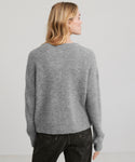 A person with long blonde hair is shown from the back, wearing the Hayes Crewneck Cardigan in gray and black jeans against a plain light background.