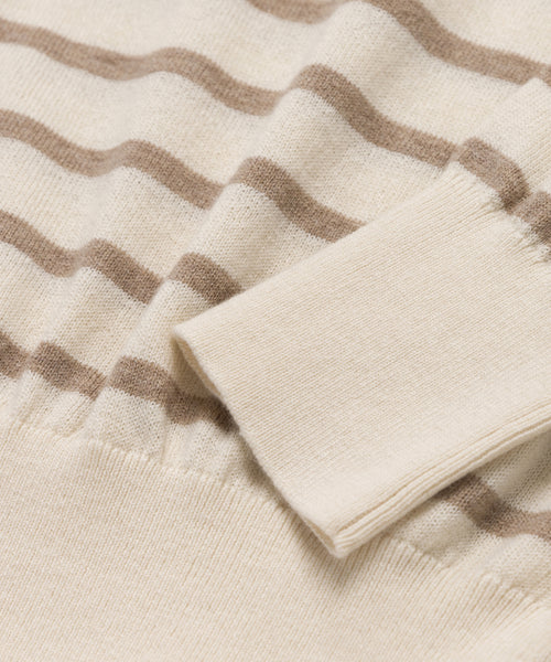 Close-up of the Avery Crewneck sweater in cream with light brown stripes. The image highlights the cotton-merino knit’s ribbed cuff and waistband, showcasing its soft texture and precise finishing.