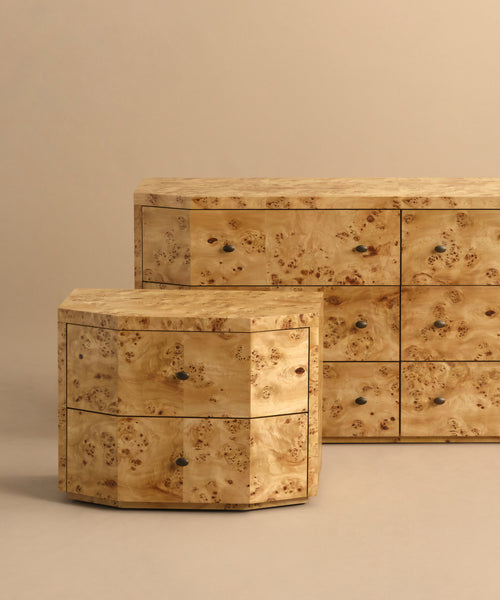 Two Carbon Nightstands with a light burl wood finish and rounded edges are set on a beige background. These modern pieces feature small round metal knobs on their drawers.