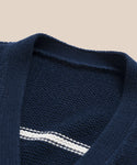 Close-up of the Chloe Cardigan in navy with an ivory V-neck and a single horizontal white chest stripe, perfect for warm weather, displayed on a plain beige background.