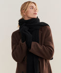 A person in a brown coat, black gloves, and the Cashmere Alpine Scarf looks to the side against a plain background.