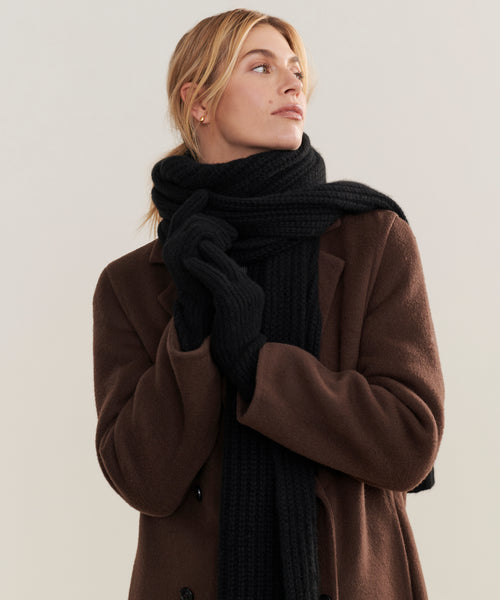 A person in a brown coat, black gloves, and the Cashmere Alpine Scarf looks to the side against a plain background.