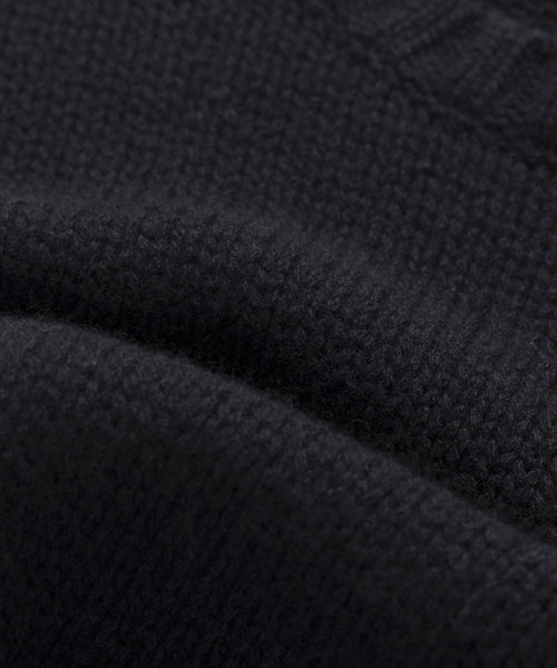 Close-up of the Cashmere Amelia Crewneck, highlighting its textured black cashmere, visible stitching, and soft folds in the luxurious knit fabric.