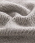 Close-up of soft, light gray knit fabric with a wavy texture and visible stitches, capturing the warmth and coziness of the Cashmere Amelia Crewneck sweater.