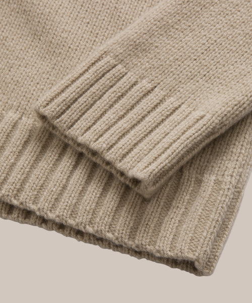 Close-up of the ribbed cuffs and hem on the beige Cashmere Amelia Crewneck, highlighting its texture and stitching details against a neutral background.