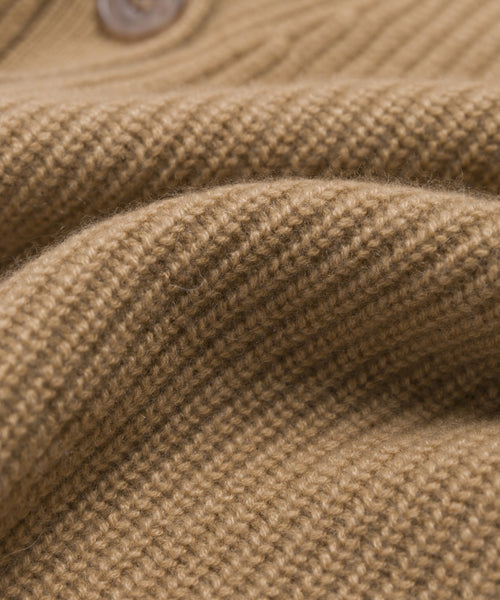 A close-up of the light brown, ribbed knit fabric on the Cashmere Cocoon Cardigan, featuring a visible top button. The pure cashmere texture and weave are clearly highlighted.