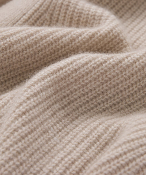 Close-up of soft, beige knit fabric with a ribbed texture. Gentle folds and fine fibers highlight the cozy warmth—ideal for the Cashmere Cocoon Cardigan, wrapping you in comfort.