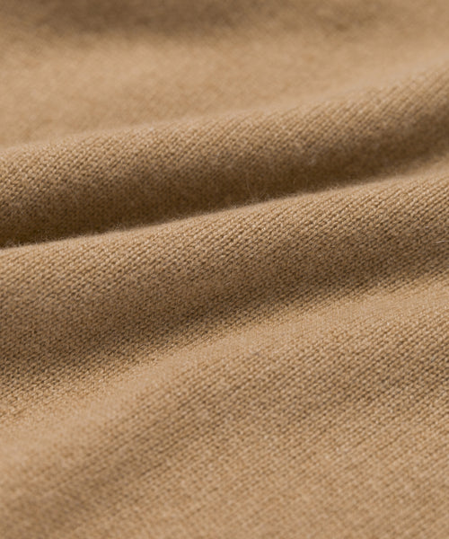 Close-up of the Flynn Cashmere Sweater’s soft, light brown fabric with a smooth, slightly fuzzy texture and gentle folds—evoking cozy comfort.