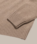 A close-up of the Cashmere Oversized Crewneck in beige showcases the ribbed cuff and hem, with soft, textured fabric that emphasizes its relaxed pullover style.