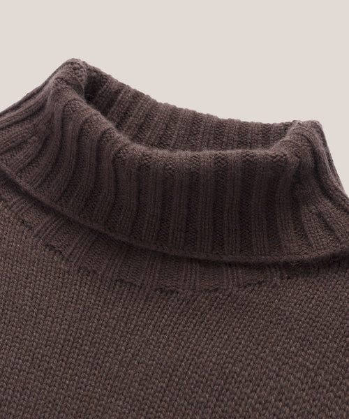 Close-up of the Cashmere Porter Turtleneck in brown, featuring ribbed collar detailing and a textured knit body, set against a plain light background.