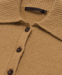 Close-up of the Cashmere Stevie Polo in camel, showcasing its oversized collar, dark brown buttons, and a black brand tag inside. The soft, textured knit fabric highlights the luxurious cashmere material.