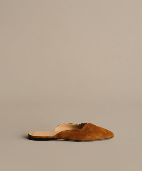 The Clara Mule is an Italian-made shoe in cognac brown suede with a pointed toe and open back, shown on a neutral background.
