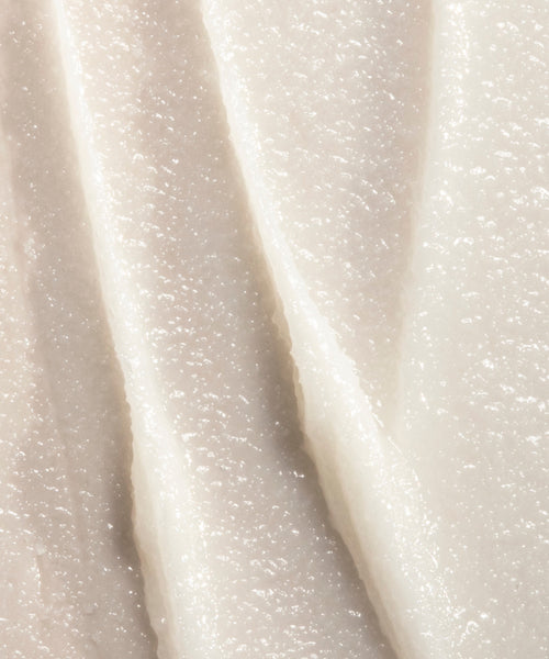 Close-up of the creamy, white texture of Conditioning Lip Balm, with smooth vertical ridges that highlight its thick, nourishing formula spread in layers.