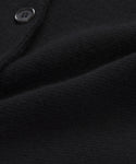 Close-up of the textured black fabric on the Cooper Cardigan, with a visible seam and part of a black button. The soft, slightly folded material highlights the quality finish of this structured cardigan.