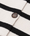 Close-up of the Cooper Cardigan’s knitted fabric, showing ivory black stripes and a brown button sewn onto one of the white stripes.