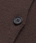 A close-up of the Cooper Cardigan’s dark brown knit fabric with a black button highlights its detailed texture and stitching—ideal for versatile styling and a structured look.