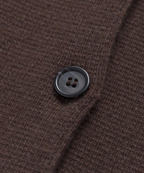 A close-up of the Cooper Cardigan’s dark brown knit fabric with a black button highlights its detailed texture and stitching—ideal for versatile styling and a structured look.
