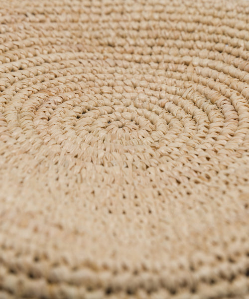 Close-up of the Crochet Raffia Sun Hat surface, showcasing a spiral pattern crafted from tightly woven natural fibers in light beige.