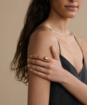 A woman in a black sleeveless dress rests her hand on her upper arm, showing off the large, round Diamond Felix Dome Ring. Her long wavy hair falls over one shoulder, set against a beige background.