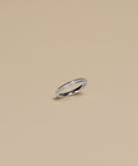 The Iris Eternity Band, crafted in white gold and adorned with a continuous row of sparkling diamonds, is elegantly presented on a simple beige background.