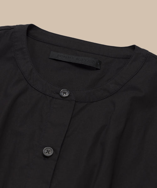 A close-up of the Lara Top, shown on a beige background, highlights its round neckline and two-button front. Crafted from Italian washed poplin.