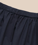 Close-up of the elastic waistband on the Lauren Skirt in black, showcasing its lightweight comfort and cotton-like feel, set against a beige background.