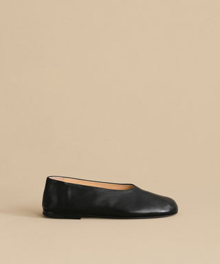 The Leather Elodie Flat, an Italian-made shoe with a rounded toe and low heel, is displayed against a plain beige background to showcase its classic feminine silhouette.