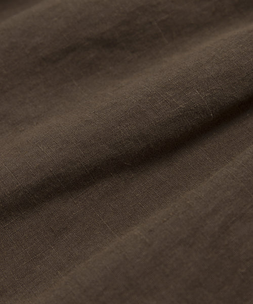 Close-up of brown fabric with a slightly rough texture and visible weave, highlighting natural folds—ideal for warm-weather outfits like the Linen Logan Short.