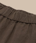Close-up of the Linen Logan Shorts waistband, featuring an elastic gathering at the top—ideal for warm days—shown against a plain beige background.
