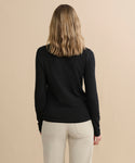 A person with shoulder-length wavy hair, seen from behind, is wearing the Long-Sleeve Slim Tee in black with light pants, standing against a plain beige background.