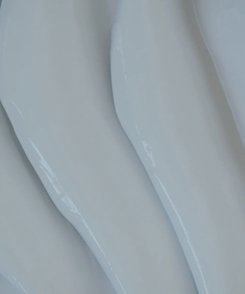 Close-up of smooth, white, wavy, glossy surfaces with soft curves—resembling abstract shapes or flowing material—much like the silky texture of Luminous Body Lotion Travel.