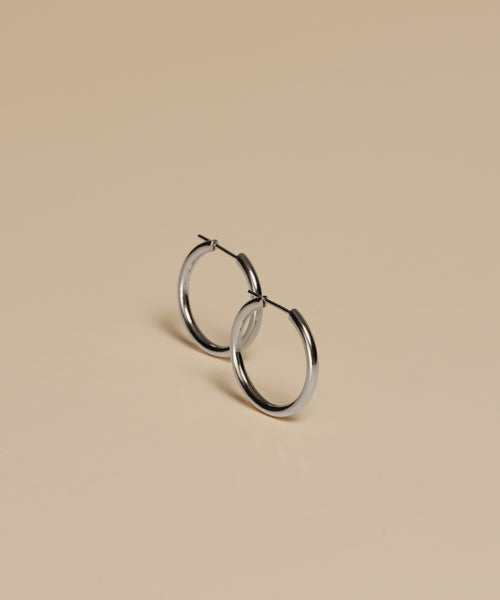 Medium Eloise Hoops are displayed on a smooth, beige surface, with gentle shadows cast beneath them.