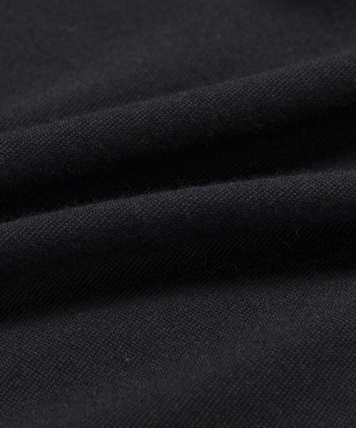 A close-up of black fabric with visible texture and folds, highlighting the soft, slightly matte surface of the 100% merino Merino Tee.