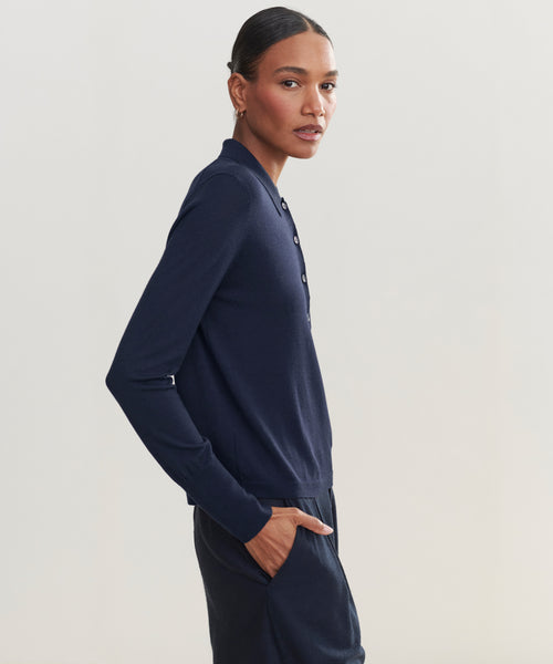 A woman with dark hair pulled back stands in profile with one hand in her pocket, wearing the Grayson Pullover against a plain light background.