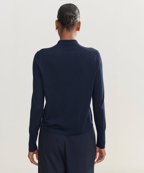 A person with their hair in a bun is shown from the back against a plain, light background, wearing a dark navy Grayson Pullover and matching pants.