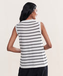 A woman with long dark hair is seen from the back wearing the Merino Tank, a sleeveless top with horizontal black stripes, paired with black pants—perfect as a stylish and versatile base layer.