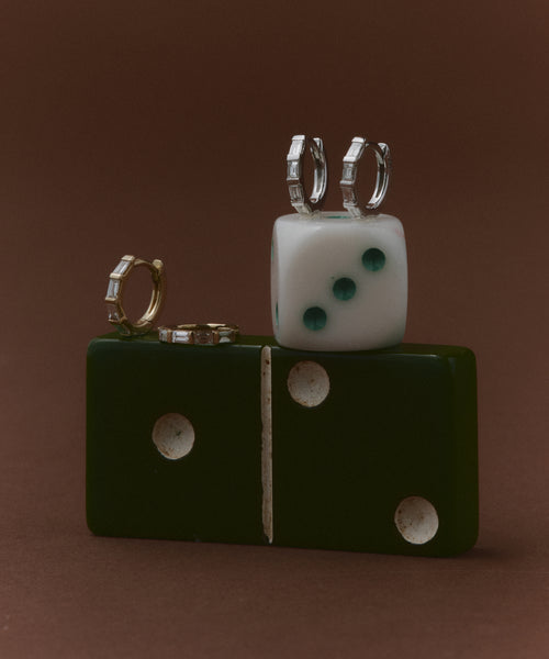 The Merit Baguette Hoops are showcased on a white die, set against a brown background—timeless heirloom jewelry with a touch of modern flair.