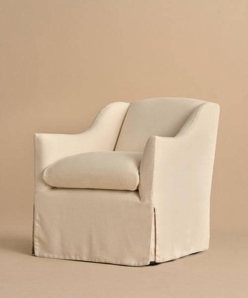 The Miramar Chair in beige linen features a slipcover, skirted base, and curved arms, shown against a matching beige background.